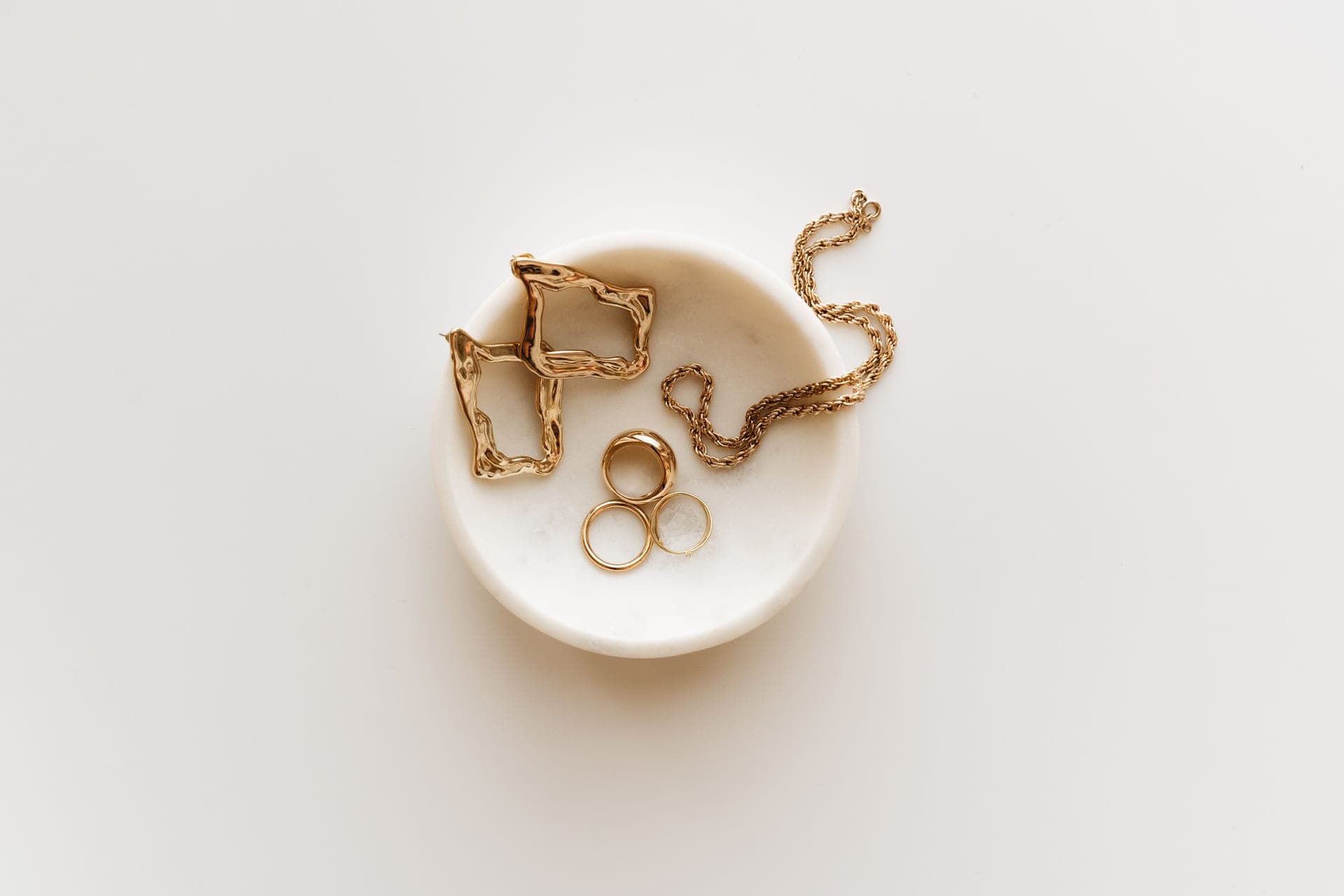 Assorted gold-toned and silver chains and earrings arranged on linen
