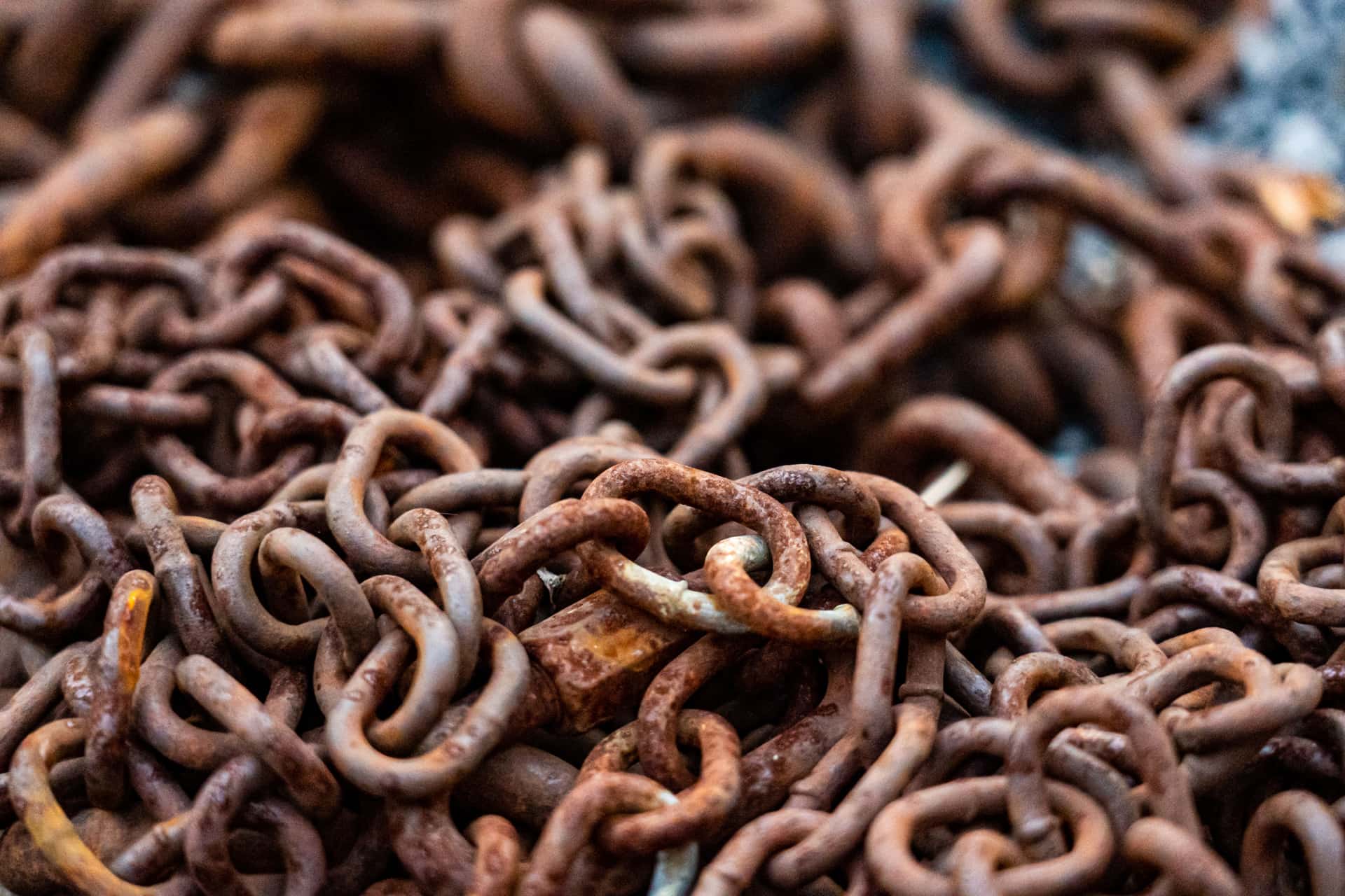 Close-up of gold-toned and silver chain links on a bone-colored surface